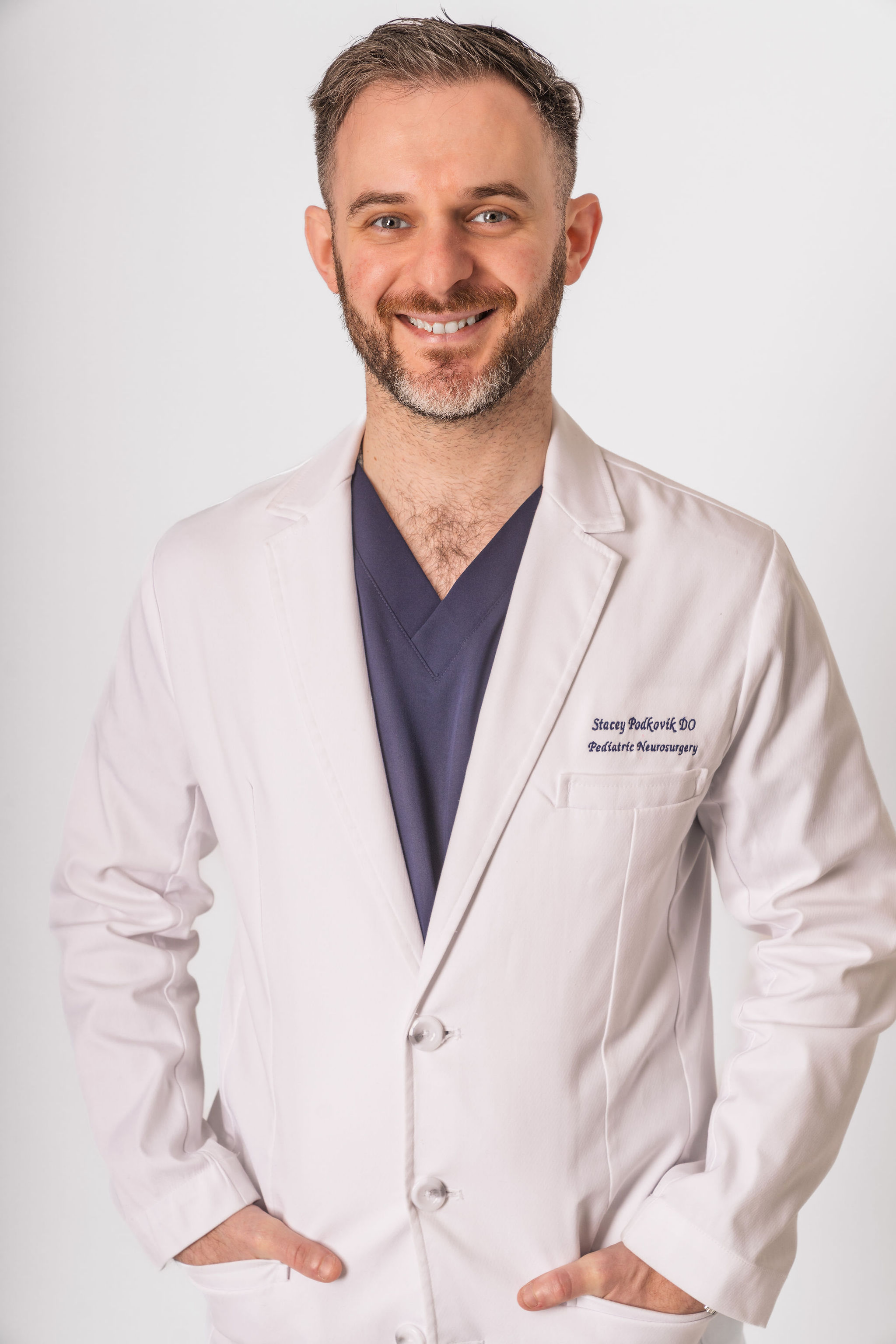 Dr. Stacey Podkovik in his white coat over navy scrubs.